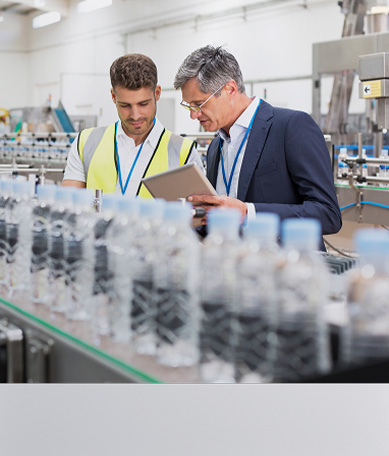 Two line workers observing manufacturing equipment
