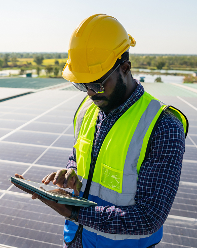 a worker wearing a hard hat reviews data on a tablet at a job site