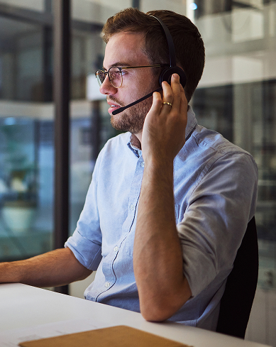 a support professional at a desk consults a client on a phone headset